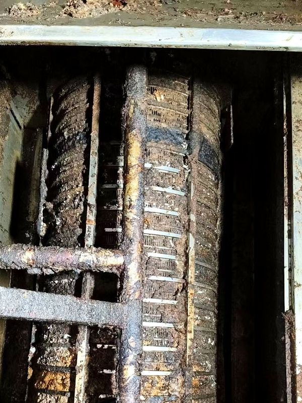 Twin-shaft dewatering screw: two screw shafts in a trough, blades and screen fully coated with slurry and grease